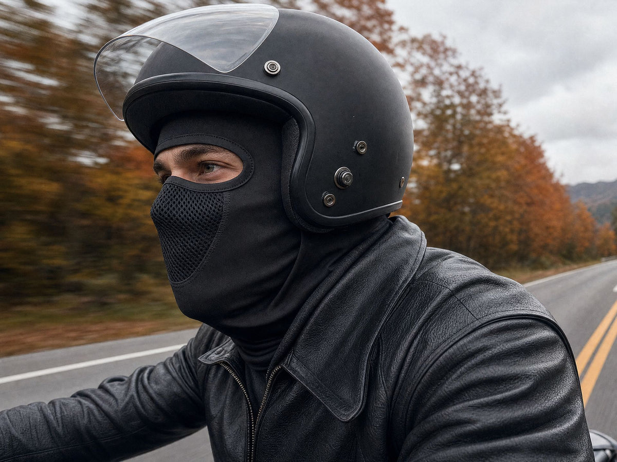 Motard portant la cagoule RONYX sous un casque ouvert, route au vent